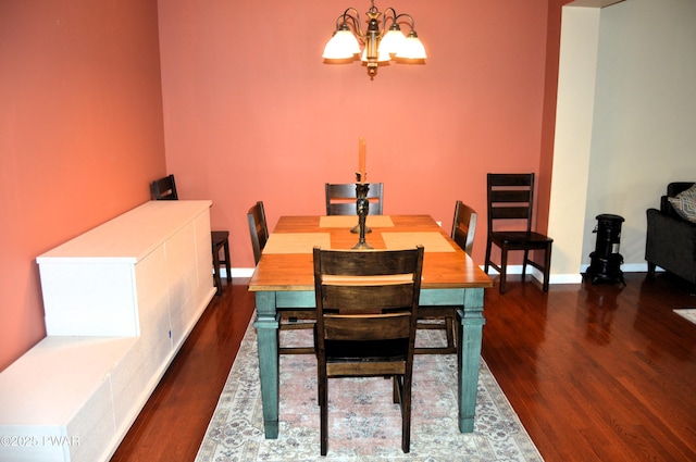 dining space with baseboards, wood finished floors, and a notable chandelier