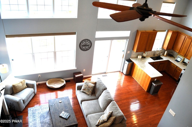 living room with wood finished floors, a wealth of natural light, and a ceiling fan