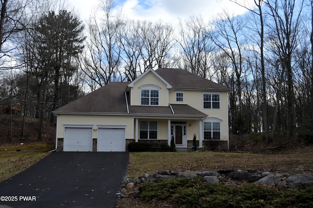 traditional home featuring covered porch, an attached garage, stone siding, and aphalt driveway