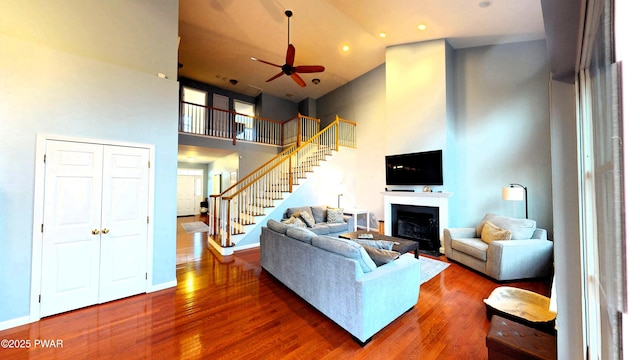 504 St Ives Ct, Bushkill, PA 18324 - living room featuring a high ceiling, stairway, ceiling fan, wood finished floors, and a fireplace