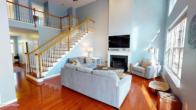 living area with stairway, a high ceiling, wood finished floors, and a fireplace