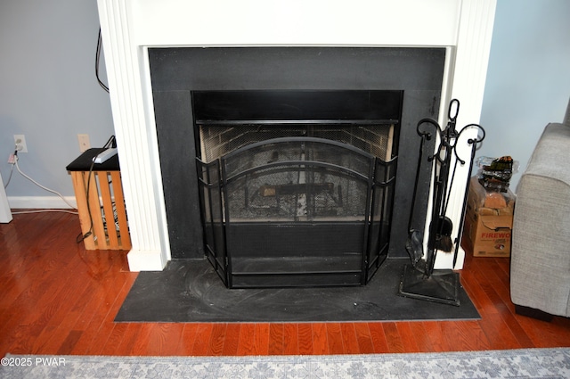 interior details featuring a fireplace with flush hearth, baseboards, and wood finished floors