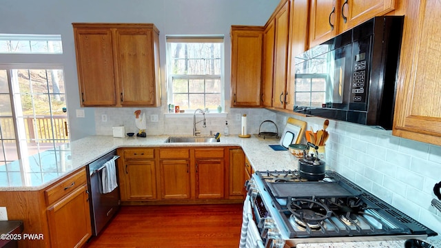 504 St Ives Ct, Bushkill, PA 18324 - kitchen with stainless steel appliances, a sink, brown cabinetry, decorative backsplash, and light stone counters