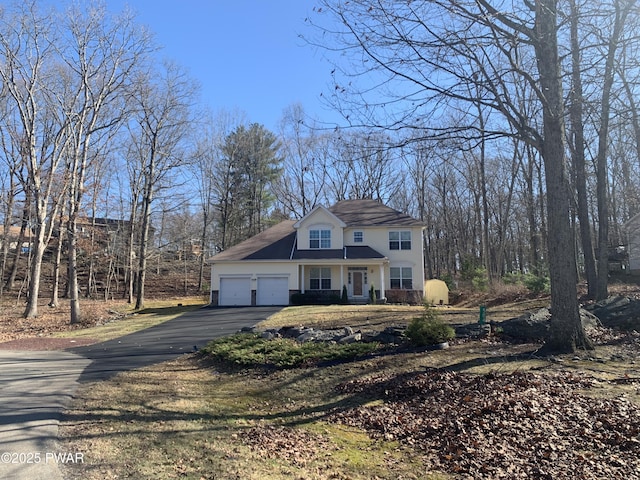traditional-style home with a garage, stucco siding, and aphalt driveway