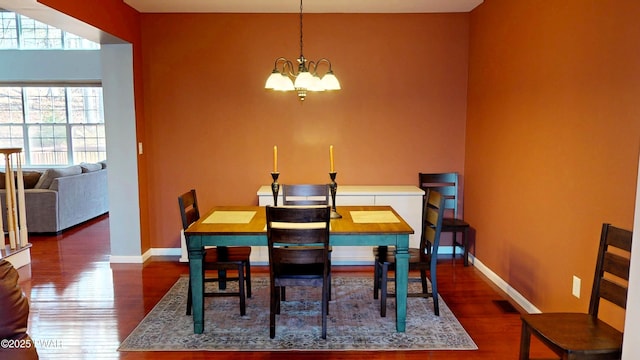 dining room featuring a chandelier, wood finished floors, visible vents, and baseboards