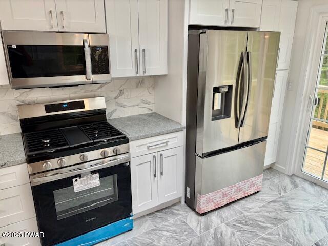 9 Wallenpaupack Dr, Lake Ariel, PA 18436 - kitchen with appliances with stainless steel finishes, white cabinets, light stone countertops, and decorative backsplash