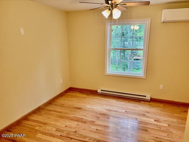 9 Wallenpaupack Dr, Lake Ariel, PA 18436 - empty room with a baseboard radiator, a wall mounted air conditioner, a ceiling fan, and light wood-style floors
