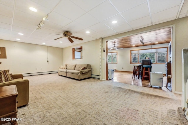 living room featuring baseboard heating, ceiling fan, and carpet floors