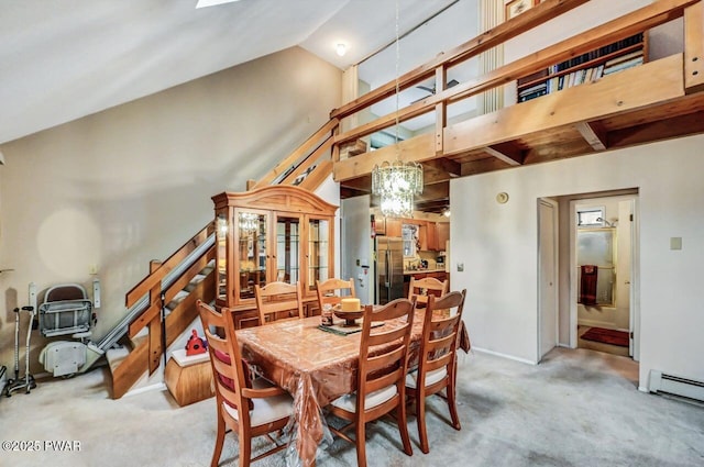 dining area featuring baseboard heating, light colored carpet, a chandelier, and high vaulted ceiling