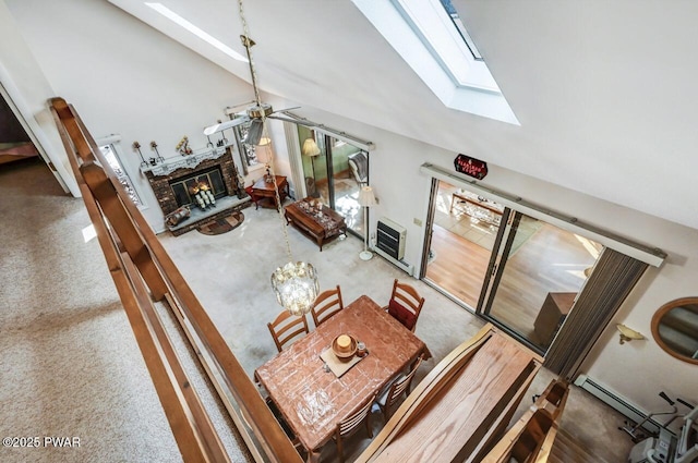 interior space with heating unit, ceiling fan, a fireplace, and vaulted ceiling with skylight