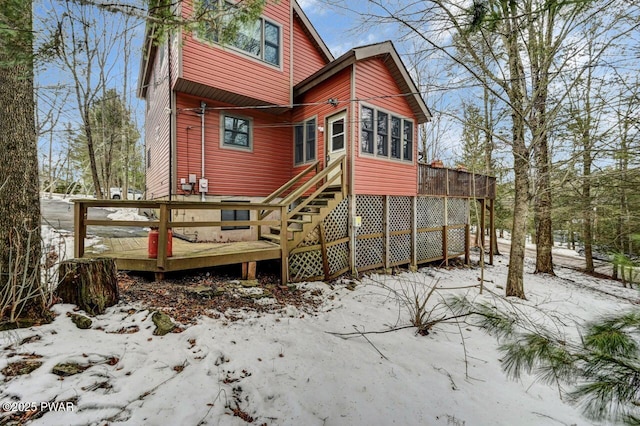 snow covered back of property featuring a wooden deck