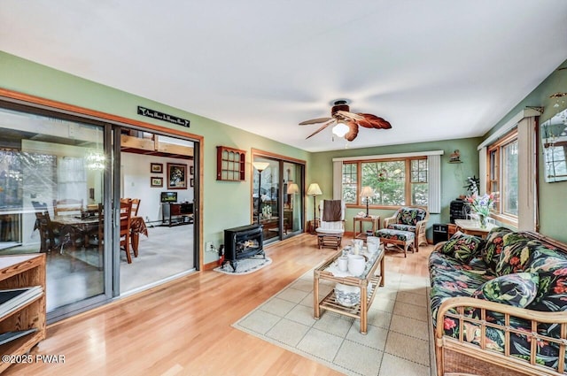 living room with ceiling fan, light hardwood / wood-style floors, and a wood stove