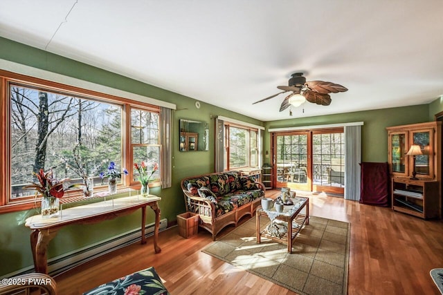 living room featuring hardwood / wood-style flooring, ceiling fan, and baseboard heating