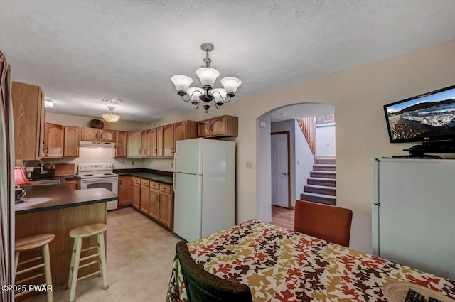 32 Forest Ln, Lake Ariel, PA 18436 - kitchen featuring white appliances, arched walkways, dark countertops, under cabinet range hood, and a chandelier