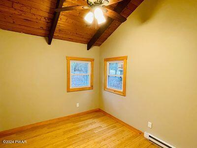 empty room featuring ceiling fan, wooden ceiling, light hardwood / wood-style flooring, lofted ceiling with beams, and a baseboard heating unit