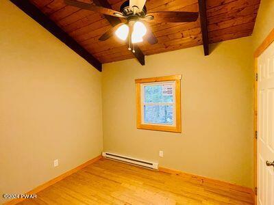 empty room with vaulted ceiling with beams, light hardwood / wood-style floors, wooden ceiling, and baseboard heating