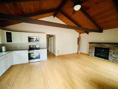 kitchen with wooden ceiling, light wood-type flooring, a fireplace, appliances with stainless steel finishes, and white cabinetry