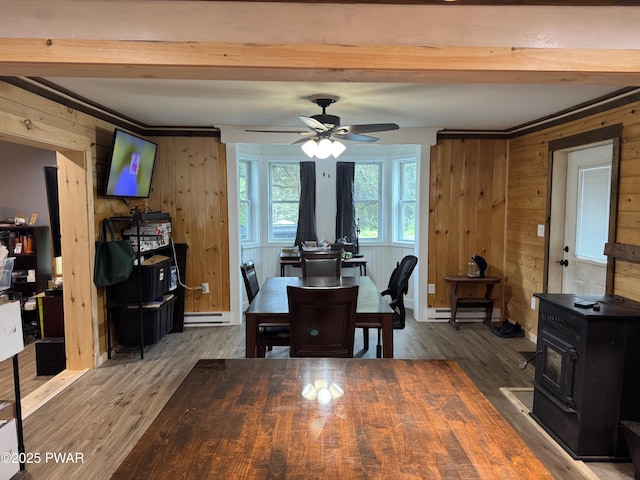 8 Kaiser Strasse, Beach Lake, PA 18405 - dining space featuring a wood stove, wood finished floors, wooden walls, a baseboard heating unit, and a ceiling fan