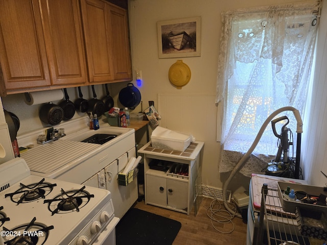 kitchen featuring white range with gas stovetop, wood-type flooring, and sink