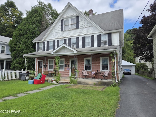 view of front of house with an outbuilding, a garage, a front lawn, and covered porch