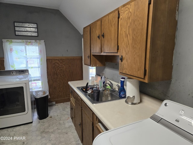 clothes washing area with sink, washer and clothes dryer, and wood walls