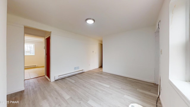 unfurnished room featuring baseboard heating and wood finished floors