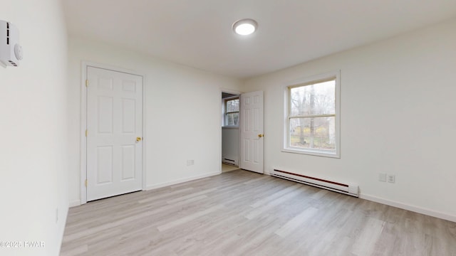unfurnished bedroom featuring light wood-style floors, baseboards, and baseboard heating