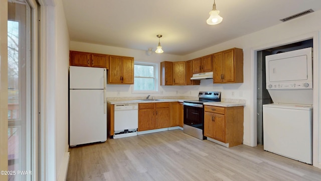 kitchen with under cabinet range hood, visible vents, white appliances, light wood-style floors, and stacked washing maching and dryer