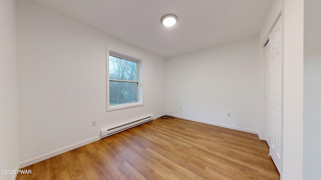 unfurnished bedroom featuring baseboard heating, baseboards, and light wood-style flooring