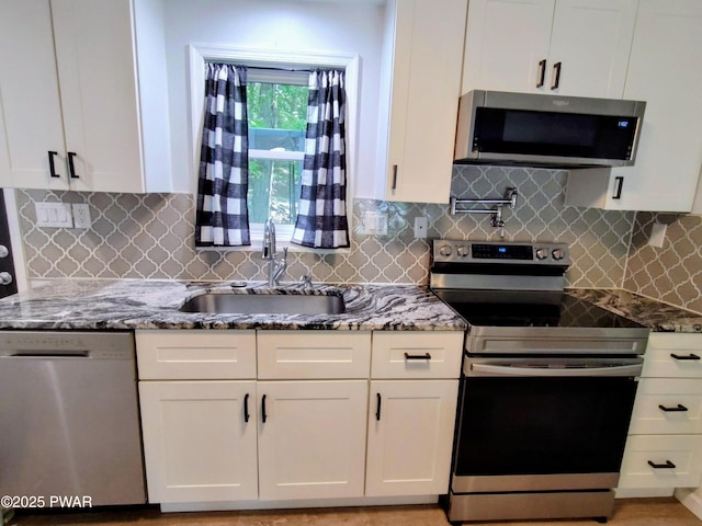 104 Radcliff Rd, Bushkill, PA 18324 - kitchen with stainless steel appliances, a sink, white cabinetry, light stone countertops, and decorative backsplash