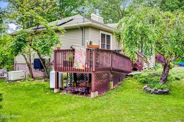 1419 Bear Dr, Bushkill, PA 18324 - rear view of house featuring a wooden deck, a lawn, and a chimney