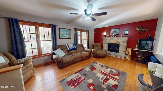 living room featuring a stone fireplace, ceiling fan, and hardwood / wood-style flooring