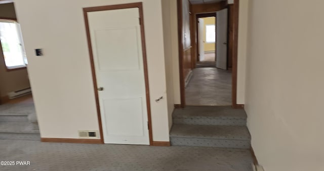 hallway featuring a baseboard heating unit, stairway, visible vents, and baseboards