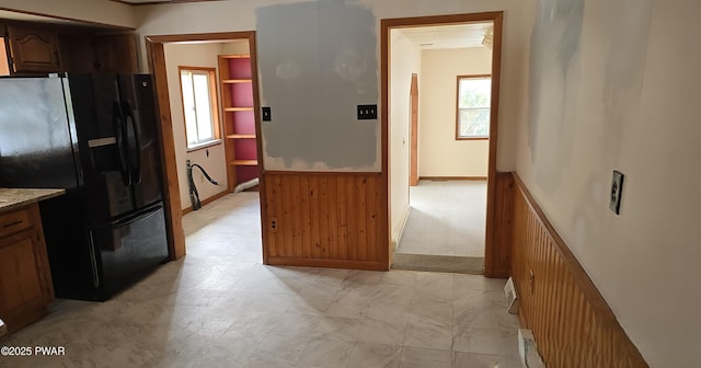 kitchen with baseboards, freestanding refrigerator, and brown cabinets