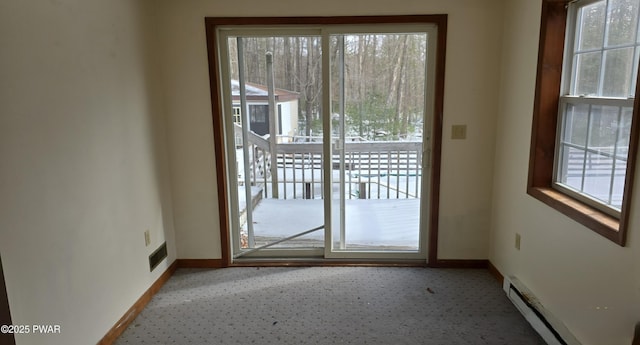 doorway featuring carpet floors, baseboards, visible vents, and a baseboard heating unit