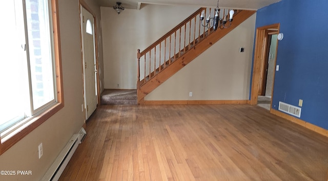 entryway with wood finished floors, visible vents, baseboards, stairway, and an inviting chandelier