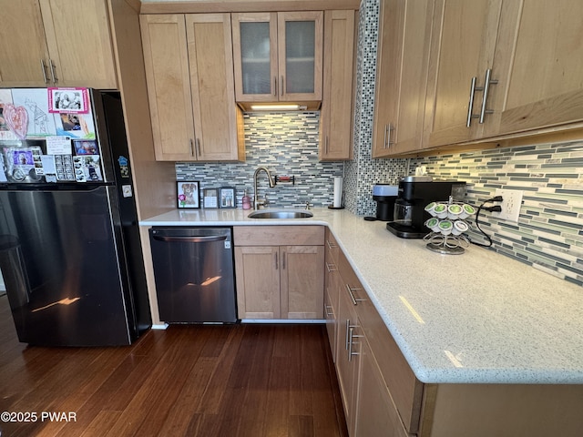 kitchen featuring dark wood finished floors, dishwasher, backsplash, freestanding refrigerator, and a sink