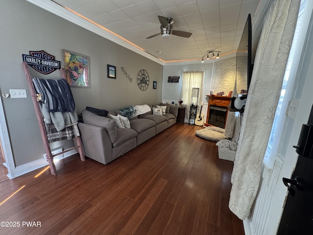 living room featuring a ceiling fan, wood-type flooring, a fireplace, and crown molding