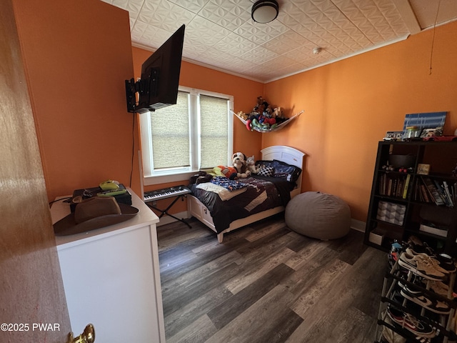 bedroom featuring an ornate ceiling, crown molding, baseboards, and wood finished floors