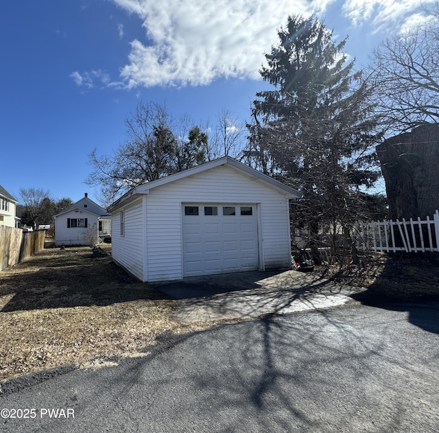 detached garage featuring fence and aphalt driveway