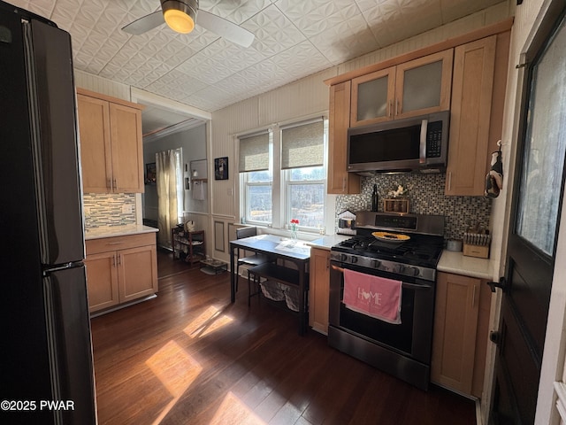 kitchen featuring range with gas stovetop, light countertops, freestanding refrigerator, stainless steel microwave, and an ornate ceiling