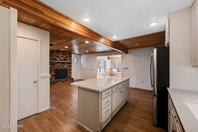 kitchen with dark wood finished floors, open floor plan, a brick fireplace, and freestanding refrigerator