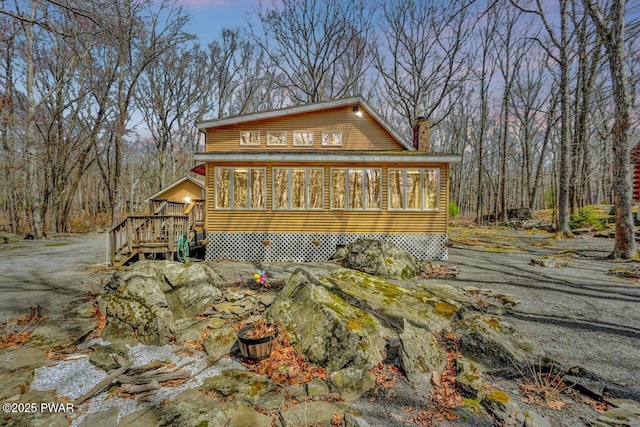exterior space featuring a wooded view and a sunroom