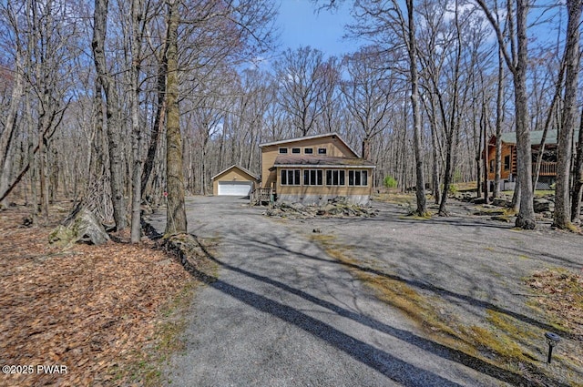 view of front of home featuring a detached garage, driveway, and a chimney
