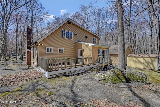 rear view of property with an outdoor structure, a chimney, and a wooden deck