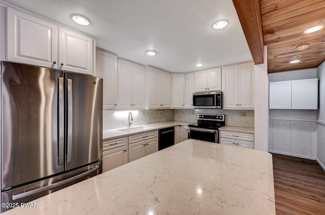 kitchen with white cabinets, stainless steel appliances, light stone counters, and a sink