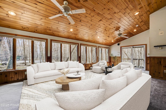 living area with carpet, ceiling fan, a wainscoted wall, and wooden ceiling
