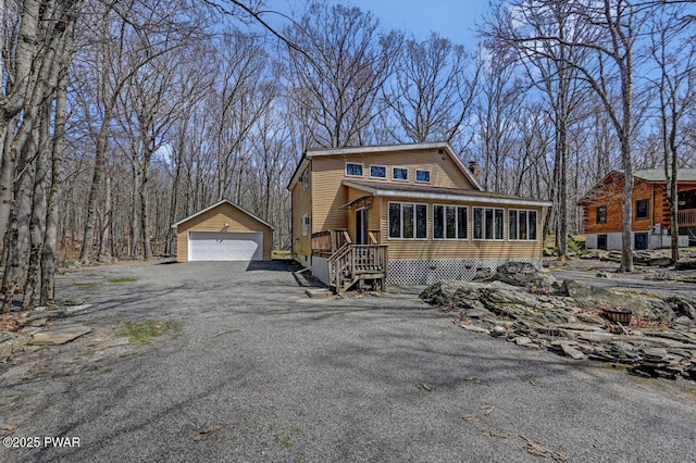 view of side of home with an outdoor structure, a detached garage, and a sunroom