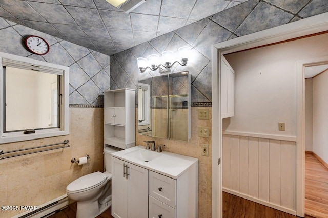 bathroom with a baseboard radiator, walk in shower, toilet, wood finished floors, and vanity