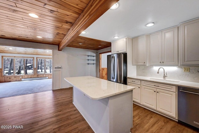 kitchen with a sink, stainless steel appliances, a kitchen island, white cabinetry, and a baseboard radiator